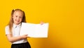 Education and school concept. Smiling little student girl with book. Copy space. Little kid looking at mockup poster Royalty Free Stock Photo