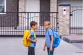 Education, school, friendship concept - two boys with backpacks talking after school outdoors