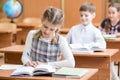 Education, school, learning and children concept - group of school kids with pens and textbooks writing test in classroom Royalty Free Stock Photo