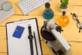 Education and science concept - microscope, book, magnifying glass, calculator, watch, blank clipboard, computer keyboard, eyeglas
