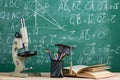 Education and sciences concept - books on the teacher desk in the auditorium, chalkboard on the background