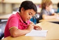 Education, student and boy in a classroom, writing and studying for a test, exam and notebook. Male child, school and Royalty Free Stock Photo