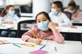 Asian school girl in mask sitting at desk in classroom Royalty Free Stock Photo