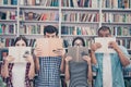 Education and teenage concept. Group of four muiti ethnic students in casual outfits are hiding behind the open books, with wide