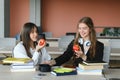 Education. Two clever modern students in black and white uniform study in a library sitting at a table with books