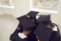 Group of graduates in square caps standing close in circle, embracing each other