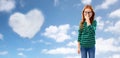 Cute red haired student girl in glasses over sky