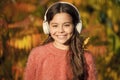 Educational and downloadable audio books for children. Kid girl relaxing near autumn tree with headphones. Music for