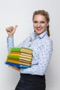 Educational Ideas. Positive Caucasian Blond Female With Heap of Books in Colorful Covers With Pleased Facial Expression Showing