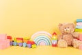 Educational kids toys collection. Teddy bear, wood rainbow, xylophone, wooden educational baby toys on yellow background Royalty Free Stock Photo