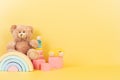 Educational kids toys collection. Teddy bear, wooden rainbow pink cubes and colorful balls on yellow background. Front