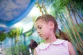 Educational process of interested little girl looking at butterfly insect sitting on her shoulder in insectarium