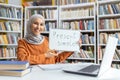 Educator in hijab teaches English grammar in library setting