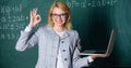 Educator smart clever lady with modern laptop searching information chalkboard background. Woman wear eyeglasses holds