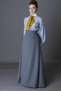 An Edwardian working class woman wearing a striped cotton blouse, mustard yellow cravat, and a grey walking skirt Royalty Free Stock Photo