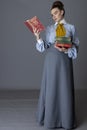 An Edwardian working class woman wearing a striped cotton blouse, mustard yellow cravat, and a grey walking skirt