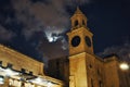 An clock tower at night against a moody overcast sky