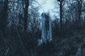 An eerie ghostly figure standing in a forest on a winters day