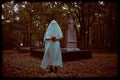 The eerie photo captures a ghost holding a jack\'s pumpkin while standing in a graveyard at dusk. Halloween