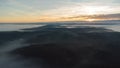 Eerie scenery of beautiful sunrise above clouds over misty mountains