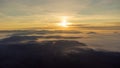 Eerie scenery of golden sunset above clouds over mountains