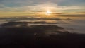 Eerie scenery of golden sunset above clouds over mountains