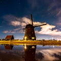 Eerie scenery of old windmills by the lake in the starry night in Alkmaar city, Netherlands Royalty Free Stock Photo