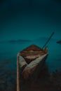 Eerie scenery of an old wooden shallop on the shore of a lake secured with a rope