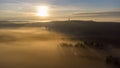 Eerie scenery of sunrise above clouds over misty mountains