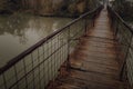 Eerie scenery of a wooden suspension bridge over the river in a cloudy day