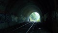 Eerie train tunnel with graffiti covered walls and trash scattered on ground Royalty Free Stock Photo