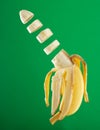 Peeled and sliced yellow banana on a green background
