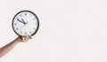 Effective time management. Female hand holding analog clock on light background, close up. Copy space. Panorama