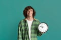 Effective time management. Happy student holding clock on turquoise background