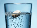 Effervescent tablet dissolving in glass of water creating bubbles Royalty Free Stock Photo