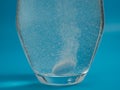 Effervescent tablet in a glass of water close-up on a blue background. Royalty Free Stock Photo