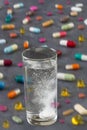 Effervescent tablet in water with bubbles with Multicolored Pills and Capsules on grey slate background Royalty Free Stock Photo
