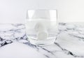 Effervescent tablets in glass with water. Fast dissolving medicine in glass on white marble background Royalty Free Stock Photo
