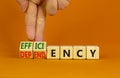 Efficiency or dependency symbol. Businessman turns cubes, changes the word dependency to efficiency. Beautiful orange table,