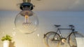 Efficient incandescent light bulb waste electricity against a tiled wall with a small bike and a plant pot. Royalty Free Stock Photo