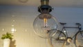 Efficient incandescent light bulb waste electricity against a tiled wall with a small bike and a plant pot. Royalty Free Stock Photo