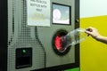 Efficient recycling: a person inserts a plastic bottle into a modern reverse vending machine with a glowing red intake Royalty Free Stock Photo