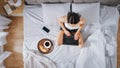 Efficient Young Millennial Girl Sitting on a Bed in the Morning, Uses Laptop Computer and Eats Cro Royalty Free Stock Photo