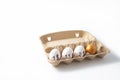 Egg carton with several white chicken eggs and one gold egg. The white eggs cost $1,$1.5 and $2. Copy space. Royalty Free Stock Photo