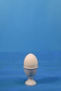 an egg in an egg cup. on a blue background. Royalty Free Stock Photo