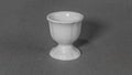 Egg cup, white, ceramic, against a solid grey cloth background Royalty Free Stock Photo