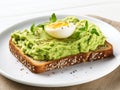 Egg cut in half on a rectangular slice of bread spread with avocado cream