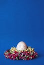 An egg with a cute painted face on a classic blue background. The classic blue flower is the trendy color of the year Royalty Free Stock Photo