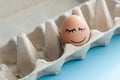 An egg with drawn emotions of happiness and pacification in an box