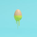 Egg dripping with yellow paint on blue background Royalty Free Stock Photo